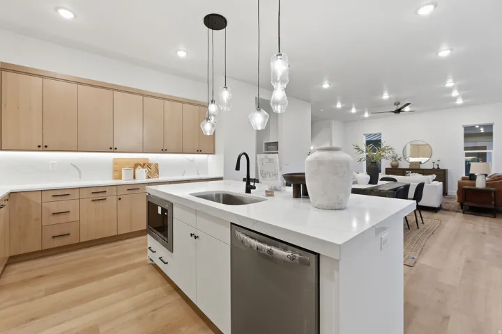 Kitchen featuring light wood-finish cabinetry, white countertops, a large island with an undermount sink, and pendant lighting