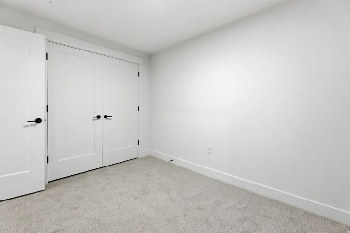 White walls, light-toned carpet, and solid core doors with matte black hardware