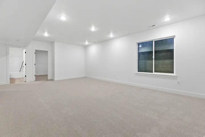 Expansive carpeted area with recessed lighting, a large window, and white trim