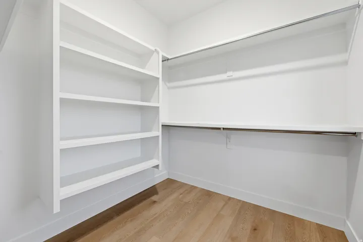 Built-in shelving, wood-finish flooring, and multiple garment rods