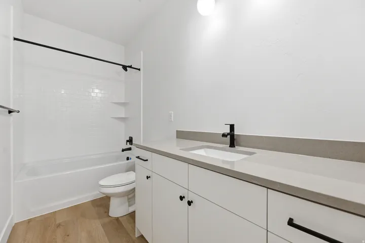 White subway tile shower surround with integrated shelving and a white tub