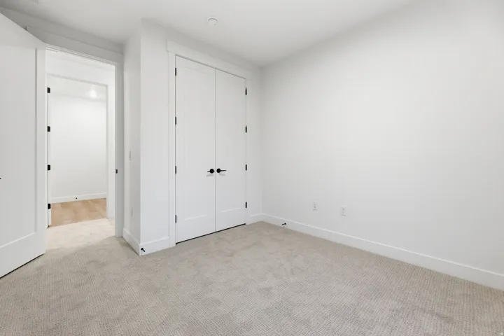 Neutral tone wall paint, light-toned carpeting, white trim, and white doors with matte black hardware