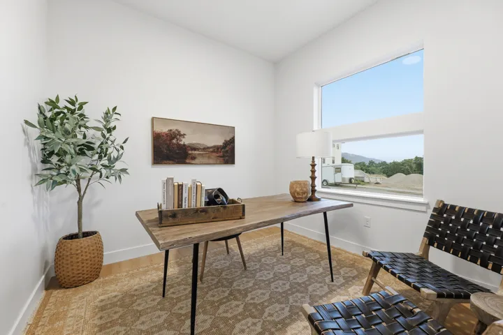 Light-filled room with wood-finish flooring, white walls, and a large horizontal window