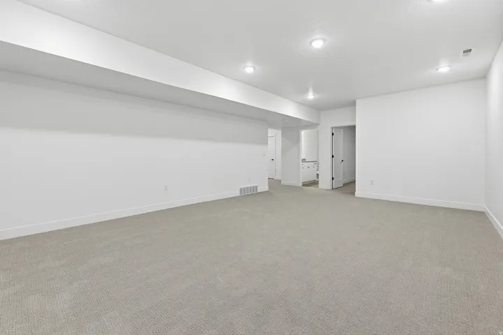 Expansive carpeted area with recessed lighting and neutral wall finishes