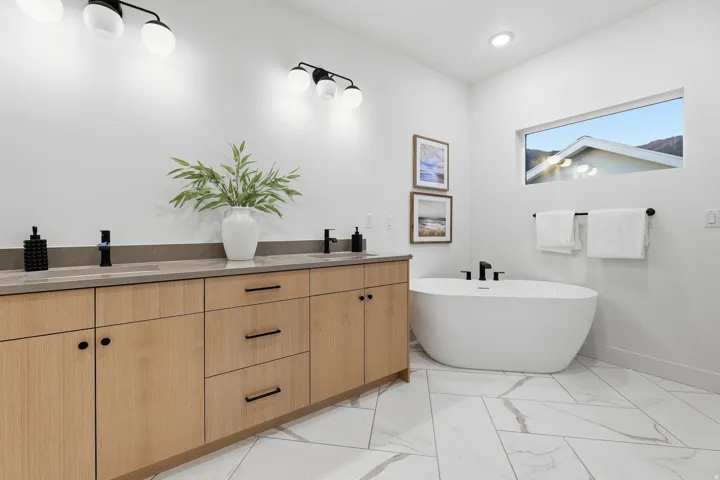 Double vanity with light wood-finish cabinetry and dark hardware