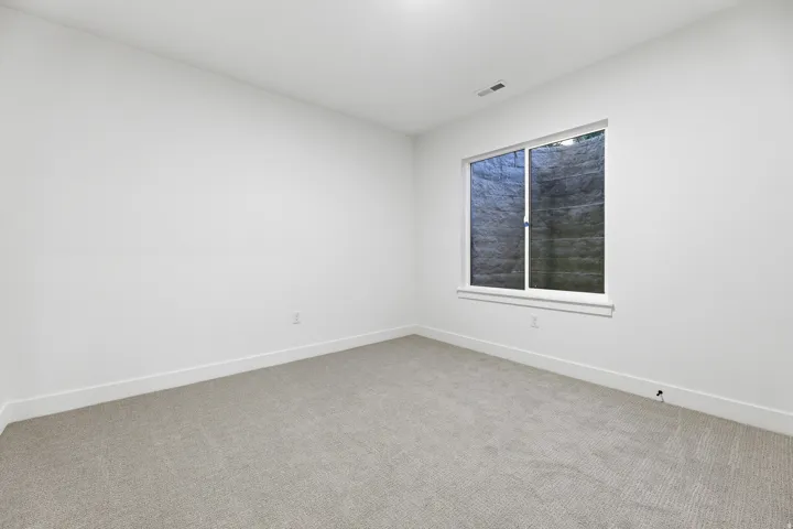 Wall-to-wall carpeting with light-toned walls and a single window