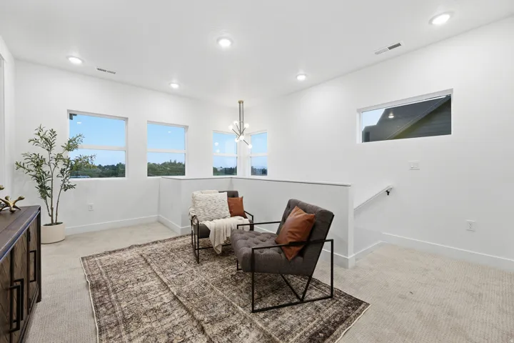 Recessed lighting, multiple windows, contemporary light fixture, half-wall railing, and carpet flooring