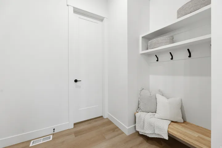 Built-in bench with wood-finish surface, floating shelves, and matte black coat hooks