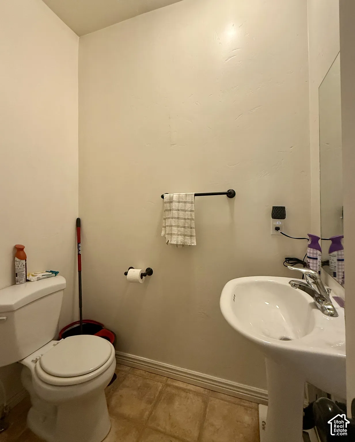 Pedestal sink with chrome faucet, toilet, and wood-finish flooring