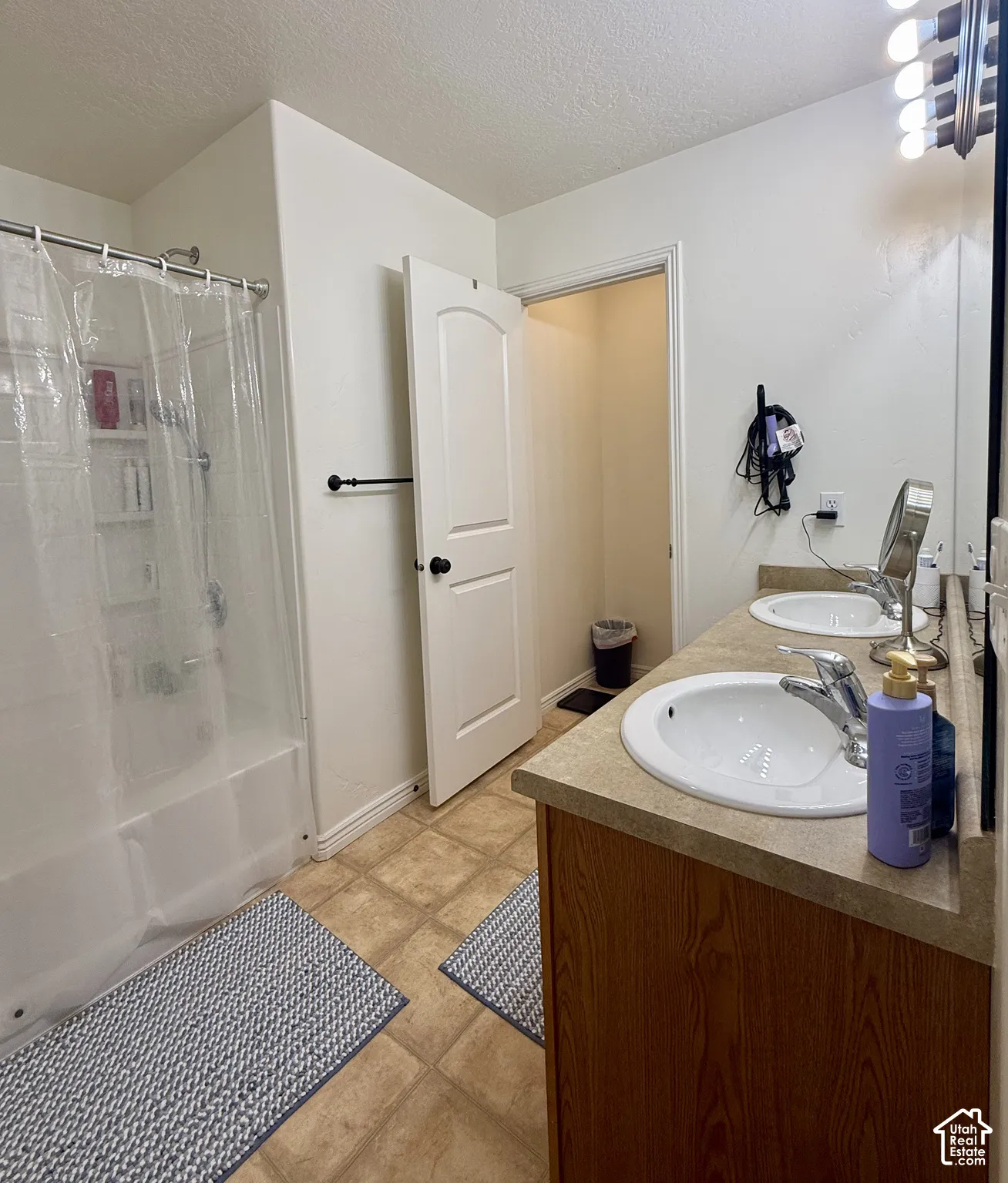 Bathroom featuring a dual vanity with integrated sinks, a tub/shower combination, and tile flooring