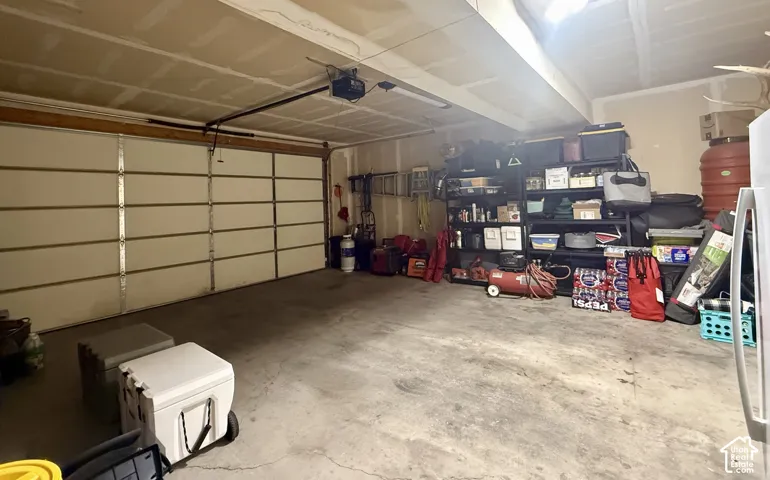 Garage space featuring a built-in garage door opener, concrete flooring, and overhead lighting
