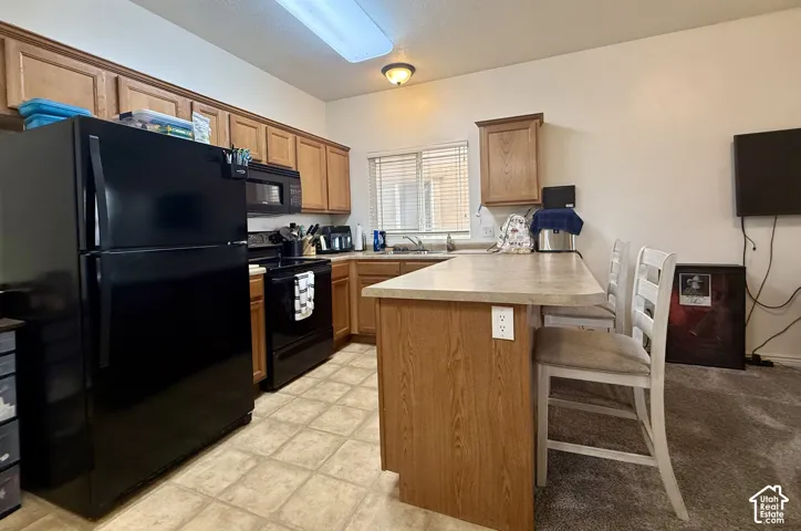 Kitchen featuring wood-finish cabinetry, tile flooring, and a breakfast bar with an integrated countertop
