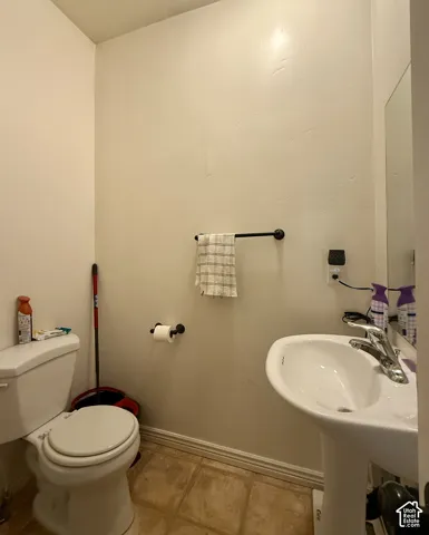 Pedestal sink with chrome faucet, toilet, and wood-finish flooring