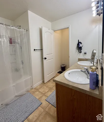 Bathroom featuring a dual vanity with integrated sinks, a tub/shower combination, and tile flooring