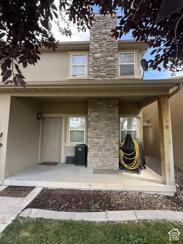 Stucco exterior featuring a stone accent chimney and covered concrete porch