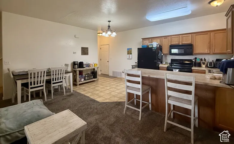 Well-appointed kitchen featuring wood-finish cabinetry, black appliances, and a breakfast bar with countertop seating