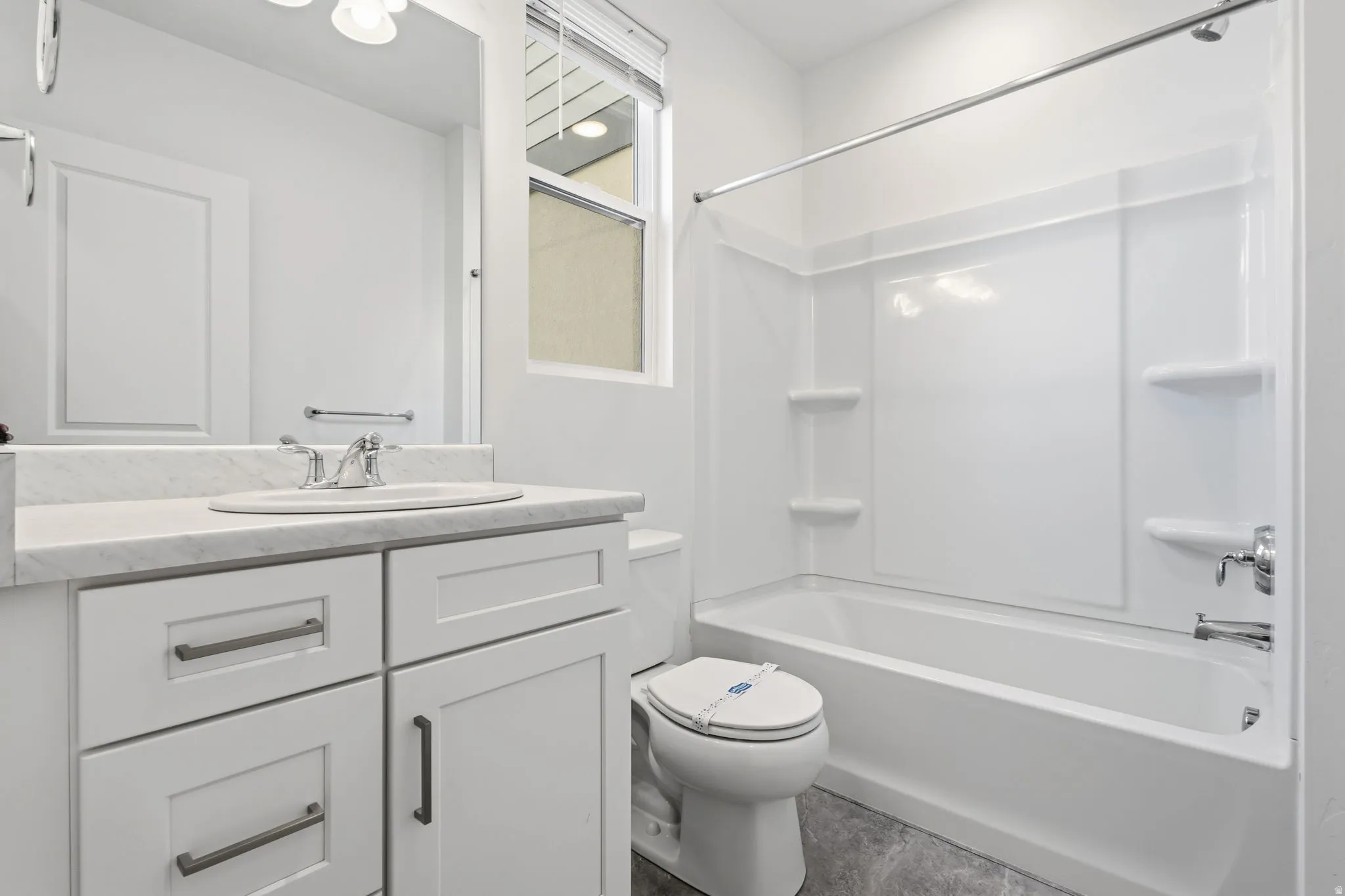 White vanity with a light-colored countertop, undermount sink, and chrome fixtures