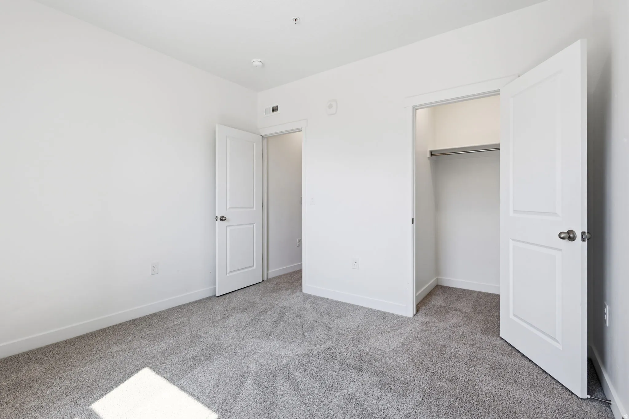 White walls, gray carpeting, and white trim throughout