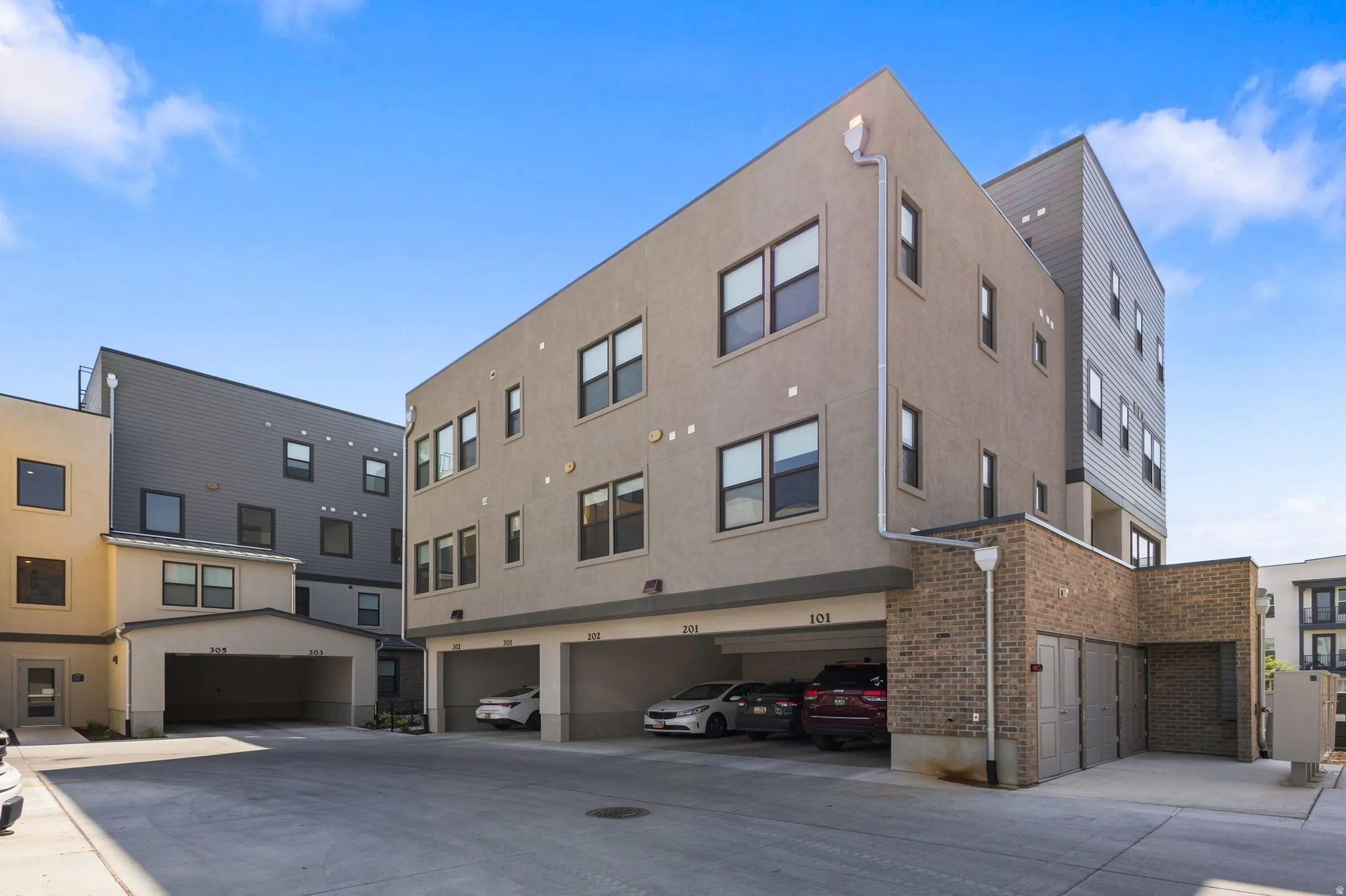 Modern stucco exterior featuring multiple windows and a covered parking area