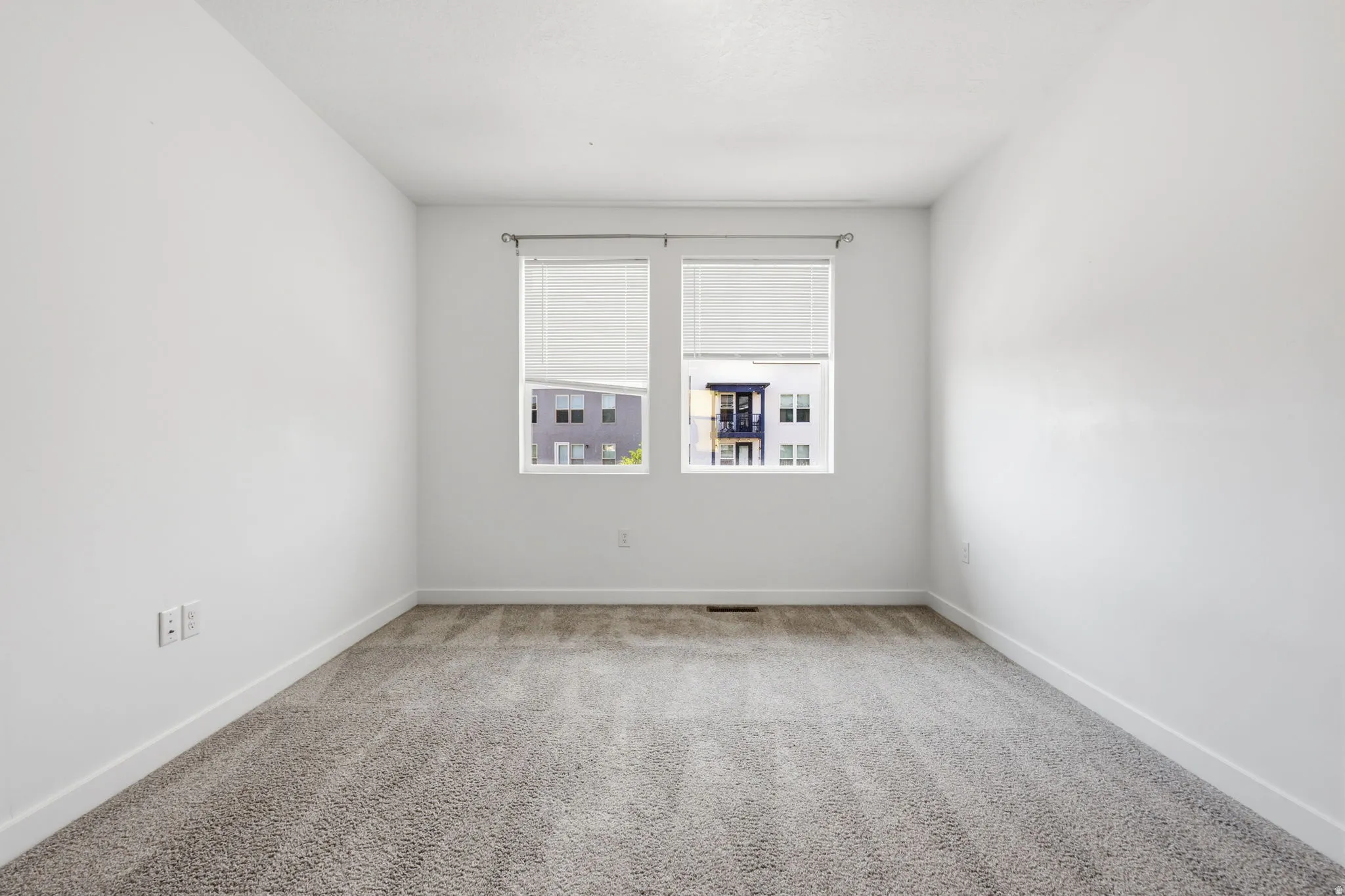 Plush gray carpeting with clean white walls and window blinds