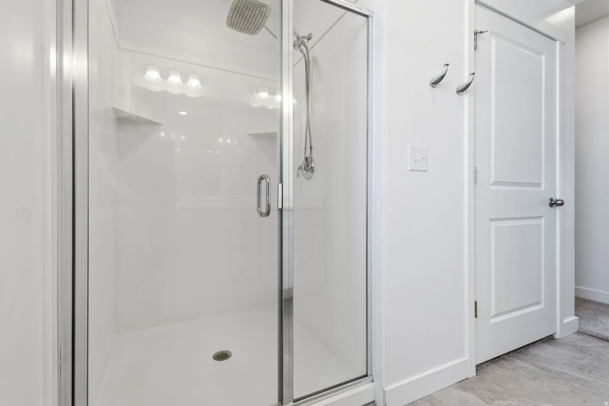 Enclosed shower with glass door and clear paneling, integrated shower niches, and a rainfall showerhead