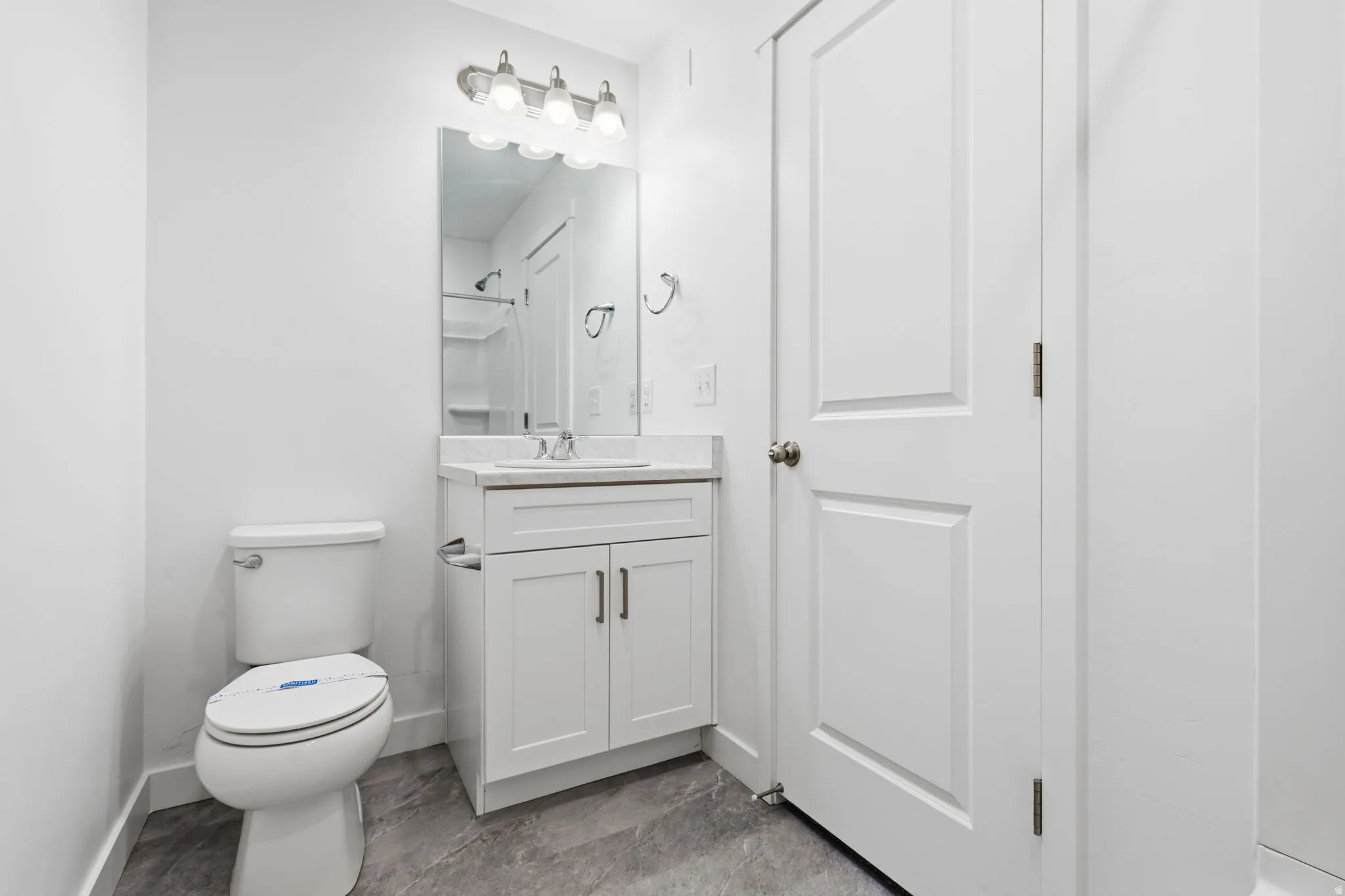 Vanity with white shaker cabinetry, white countertop, and brushed nickel hardware