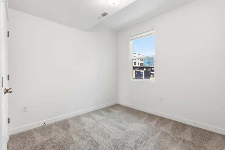 Neutral wall palette with a single window, overhead lighting, and carpeted flooring