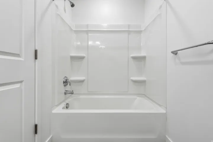 White tub and shower combination with integrated shelving