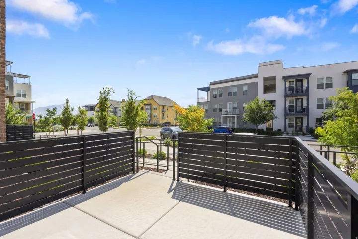 Outdoor patio area with concrete flooring, black slatted fencing, and a private gate