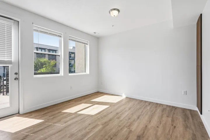 Wood-finish flooring, white walls, two window units, and a glass-paneled door