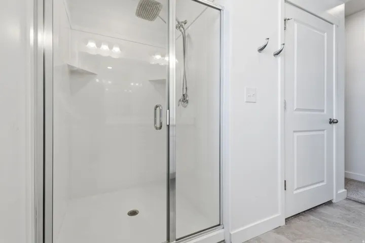 Enclosed shower with glass door and clear paneling, integrated shower niches, and a rainfall showerhead
