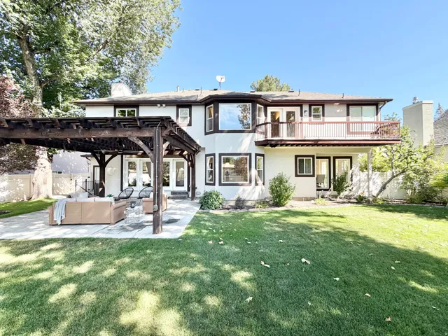 Expansive backyard with a manicured lawn, a large patio, and a built-in wooden pergola structure