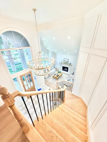 Hardwood staircase with black metal balusters, arched window, two-story entry, and checkered floor