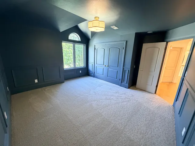 Architectural window with an arched transom, detailed wainscoting, wall-mounted light fixture, and plush carpeting