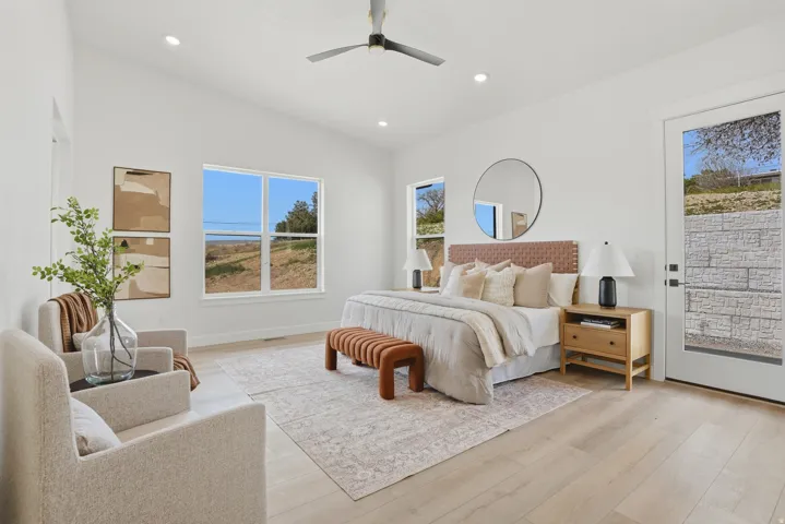 Vaulted ceiling with recessed lighting, light wood-finish flooring, multiple windows, and a glass-paneled door