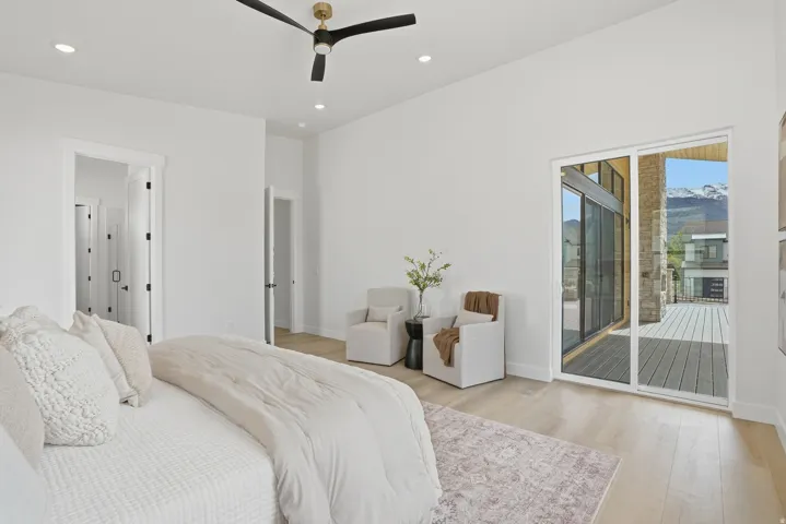 Vaulted ceilings, wood-finish flooring, recessed lighting, ceiling fan, and sliding glass door to an outdoor deck