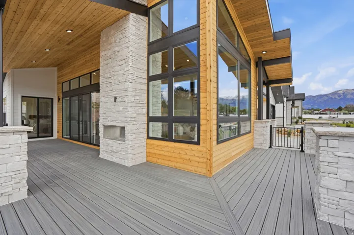 Expansive outdoor deck with composite decking, a stone-clad fireplace, and large format windows