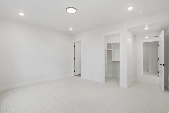 Neutral-toned carpet flooring, white walls, and recessed lighting