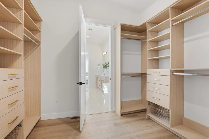 Custom closet system featuring built-in shelving, hanging rods, and drawers with gold-toned hardware
