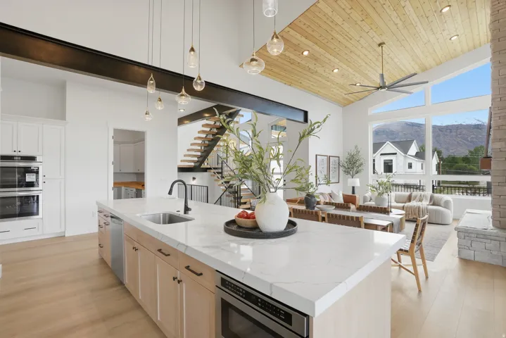 Kitchen island with a built-in sink, integrated microwave drawer, and light wood-finish cabinetry