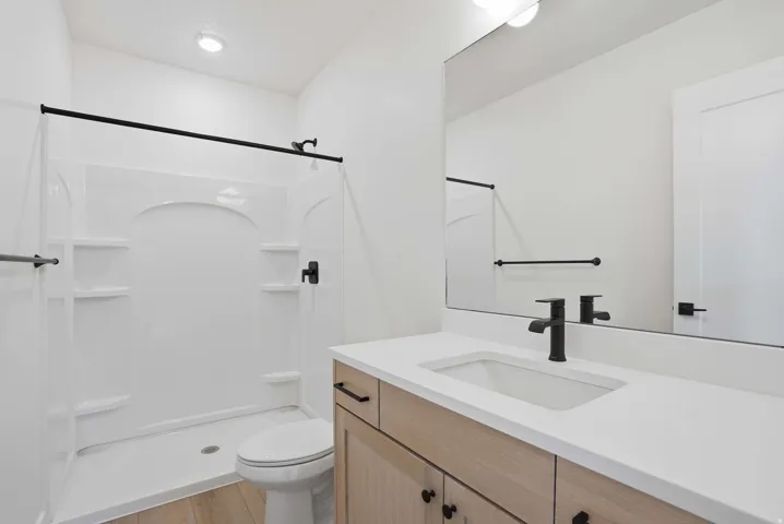 Integrated shower and toilet area featuring a black-framed shower enclosure