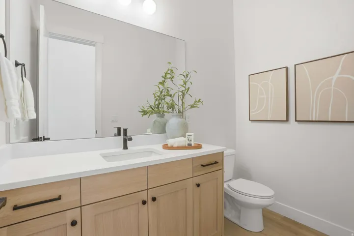 Wood-finish vanity with ample storage, integrated rectangular sink, and matte black fixtures