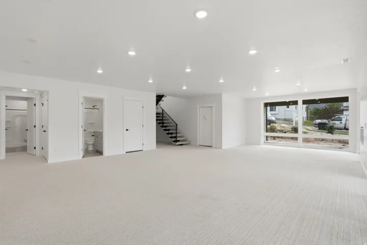 Expansive open-concept room featuring plush carpeting, recessed lighting, and large windows