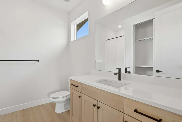 Bathroom featuring a light-toned wood-finish vanity with a white countertop, undermount sink, and matte black faucet