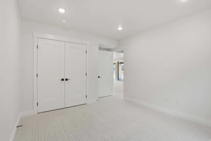 Recessed lighting, light-toned carpeting, white interior doors, and white walls