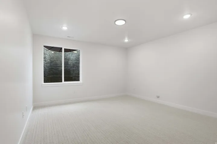Recessed lighting fixtures, white walls, white window trim, and light-colored carpet