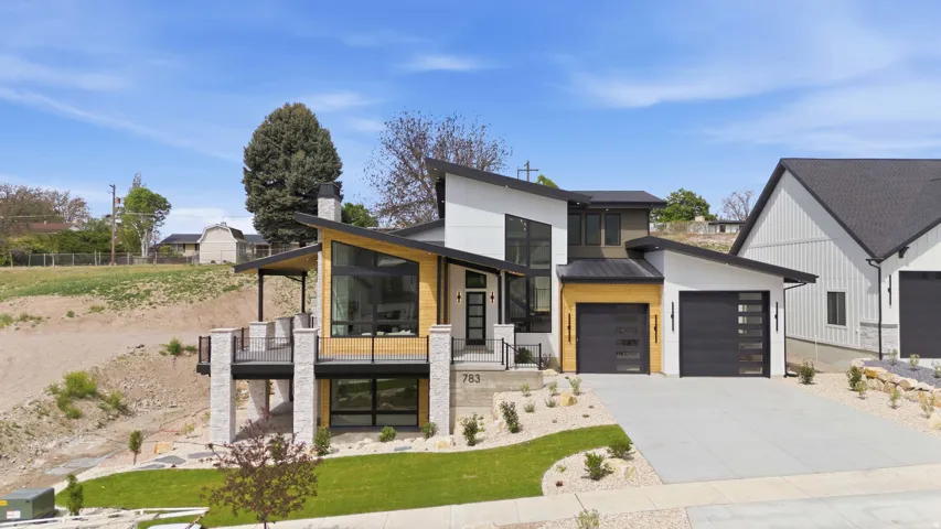 Modern architectural design featuring varied facade materials, a multi-level deck with black railings, a contemporary front entry, and multiple garage doors with frosted glass panels
