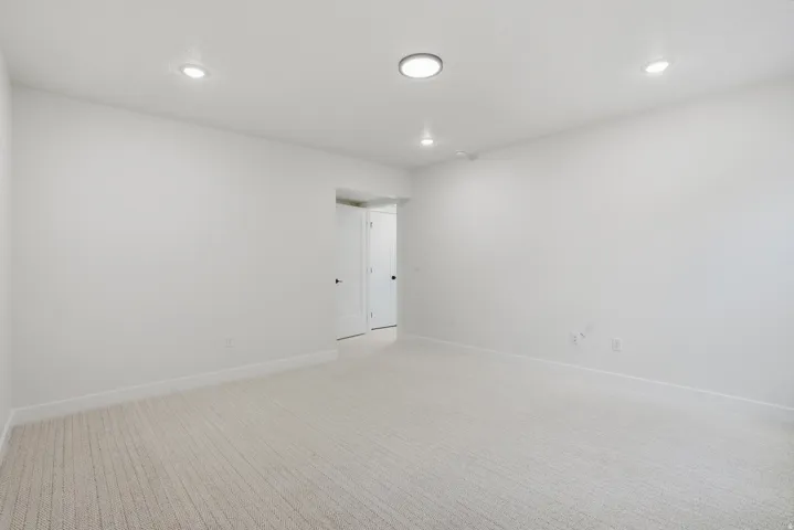 Recessed ceiling lighting, light-toned carpeting, and a white interior paint scheme
