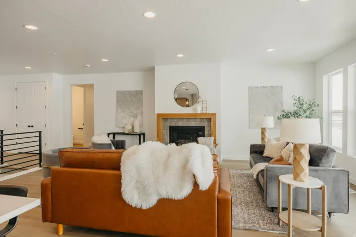 Wood-finish flooring, recessed lighting, and a fireplace with a wood mantle and tile surround