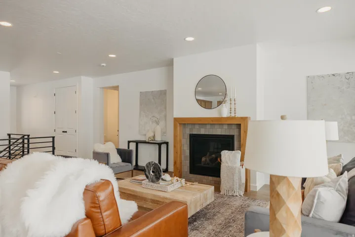 Living area featuring a fireplace with a wood-finish mantel and tile surround, recessed lighting, and white walls